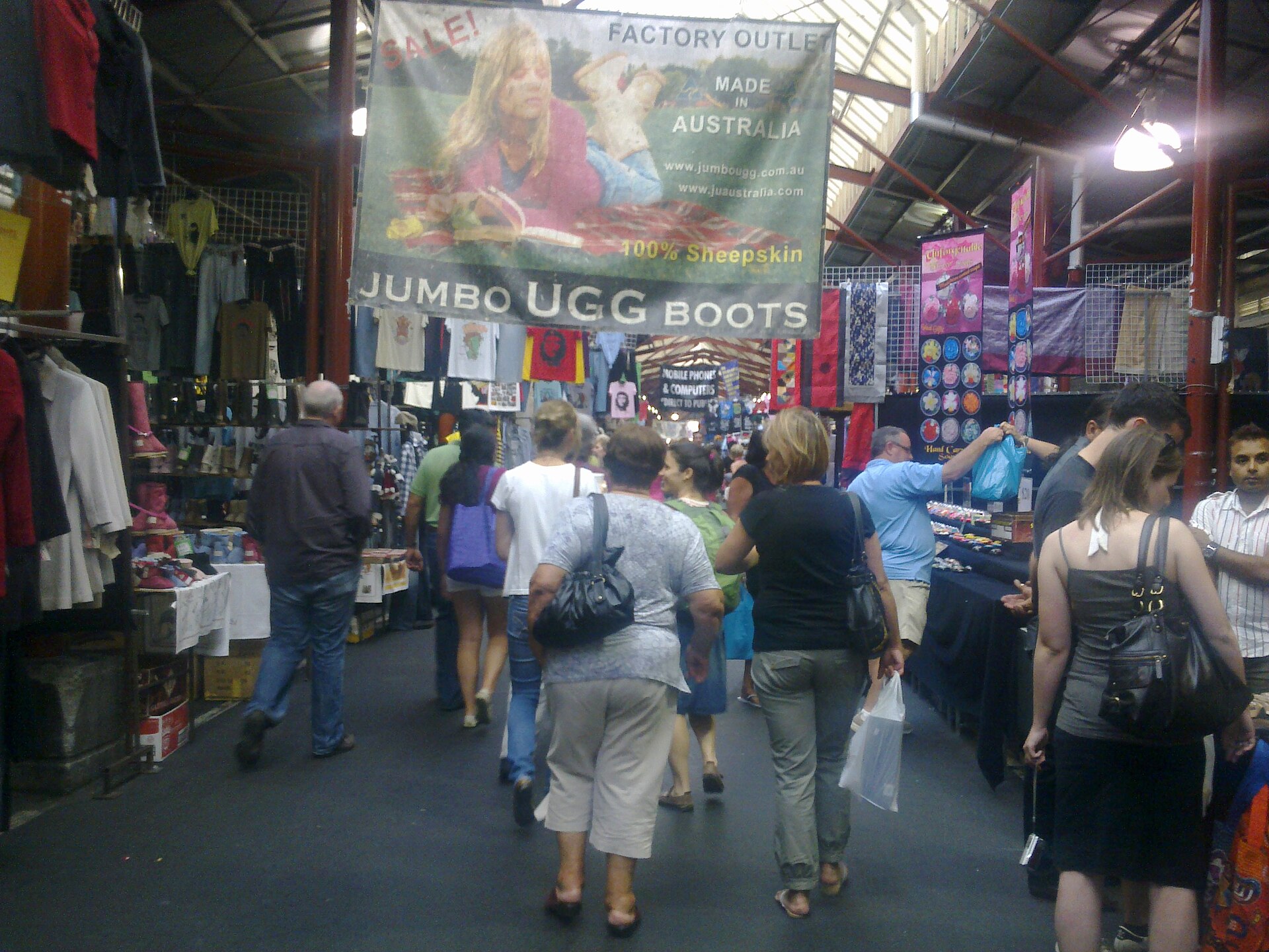 A busy market stall displays Jumbo Ugg Boots, showcasing Australian made sheepskin products and a sale.