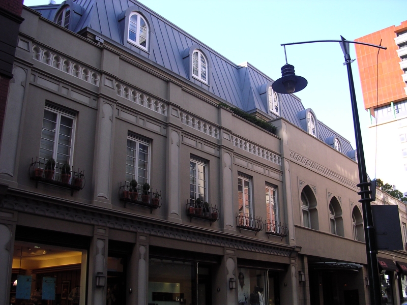 A multi-story building with arched windows stands on a street in Melbourne, showcasing local architecture.