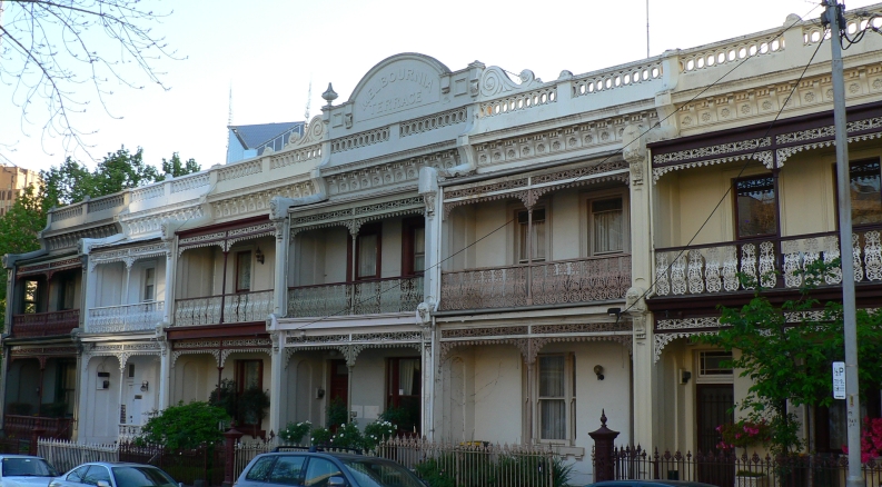 A row of ornate Victorian terrace houses lines a street in Melbourne, showcasing classic suburban architecture.